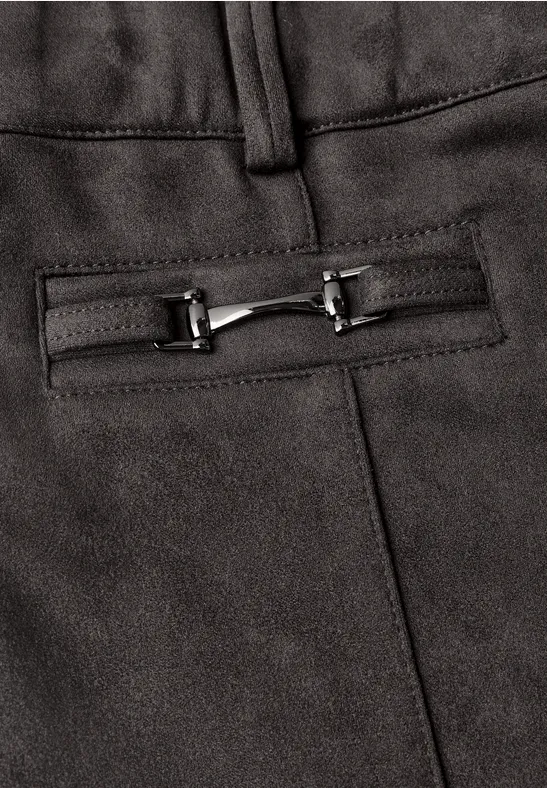 Detail einer schwarzen Hose mit Stoff und silbernem Zierbeschlag an der Tasche.