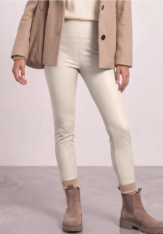 Vrouw met crème skinny broek, beige enkellaarzen en een lichtbruine blazer.