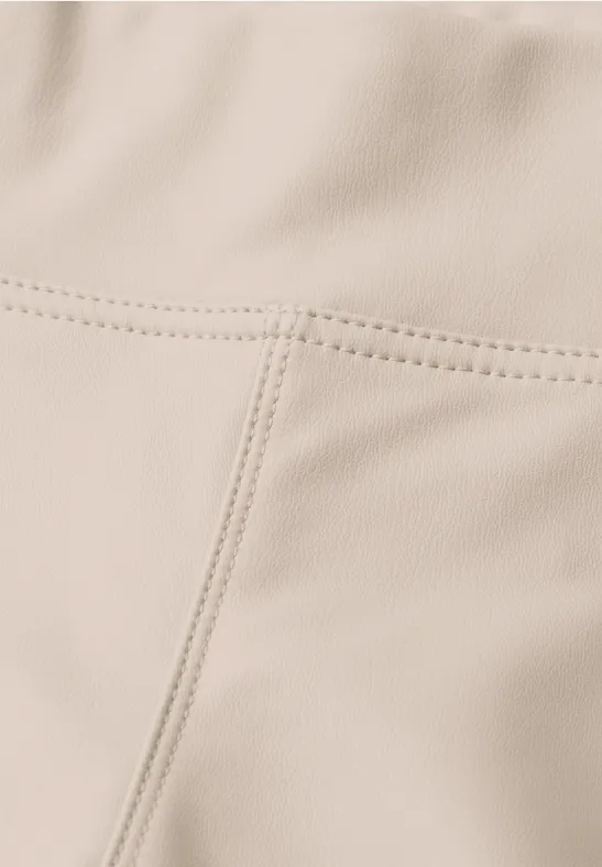 Close-up van een beige leren of kunstleren oppervlak met zichtbare naden