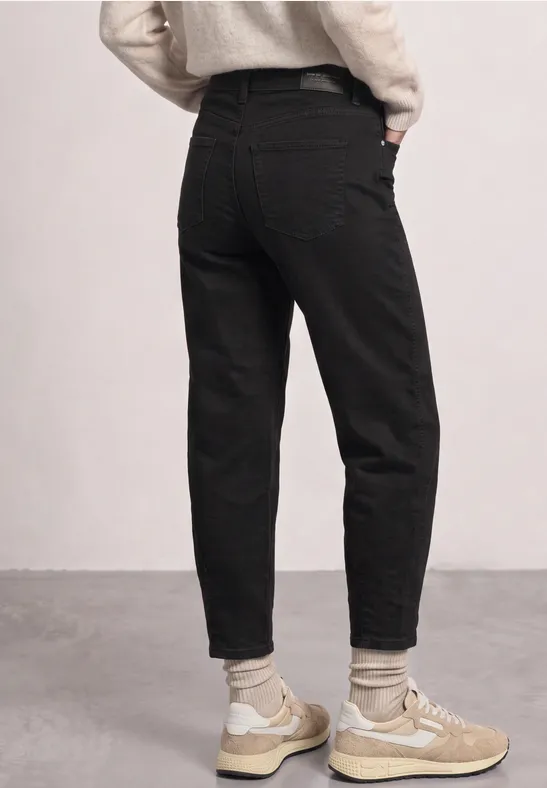 Schwarze Jeans, helle Sneaker und Socken, Person von hinten