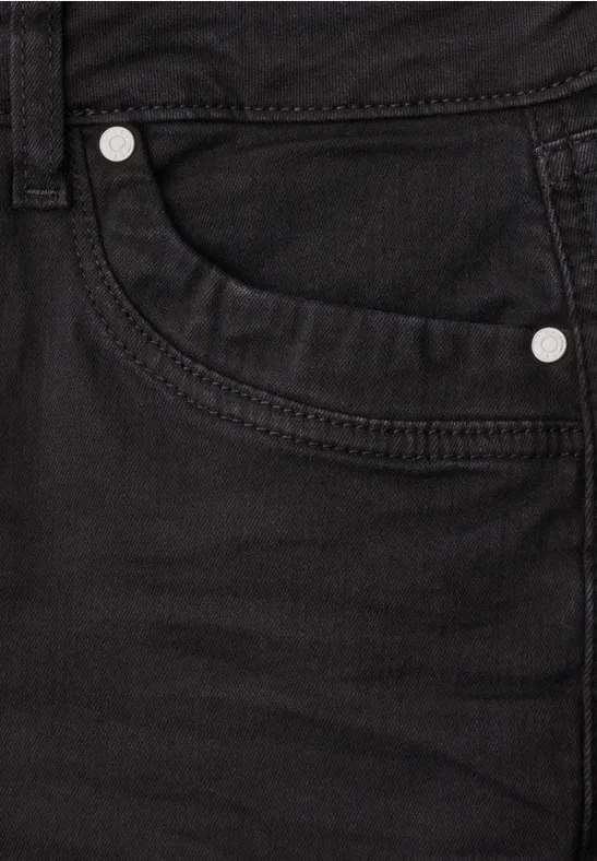 Nahaufnahme einer schwarzen Jeans mit sichtbarer Tasche und Metallnieten.