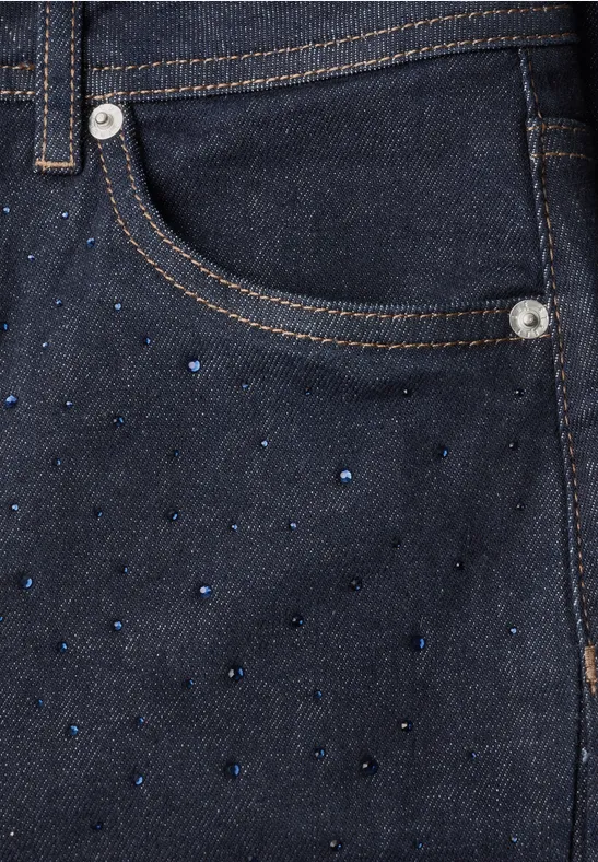 Dunkle Jeans mit seitlicher Tasche, verziert mit kleinen, glänzenden, blauen Strasssteinchen.