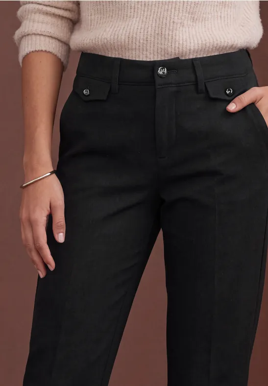 Schwarze, hoch geschnittene Hose mit aufgesetzten Taschen und Knopf, dazu ein heller Pullover.