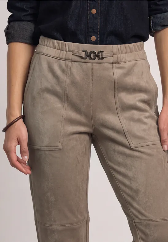 Jemand trägt eine hoch taillierte, beige Hose mit auffälligem Gürtel und Seitentaschen.