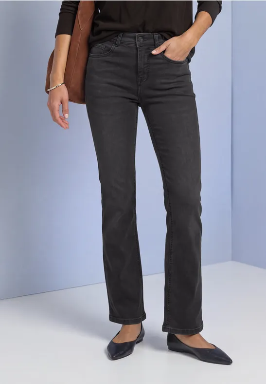 Schwarze gerade geschnittene Jeans und schwarze spitze Ballerinas, Hand in Tasche.
