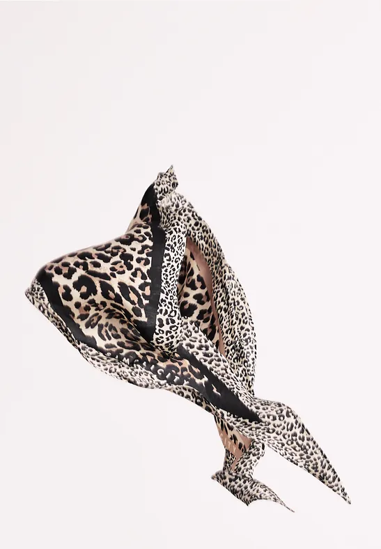 Beżowy szalik z różnymi motywami lamparta, luźno związany i lekko ułożony.