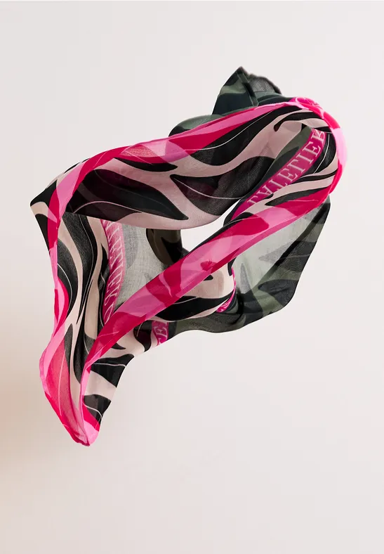 Unoszący się jedwabny szal z różowo-czarno-białym, falistym wzorem na jasnym tle.