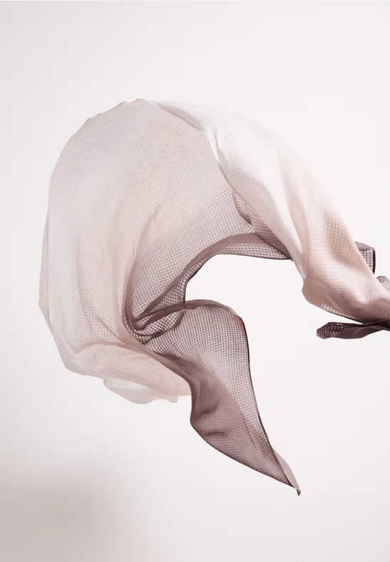 Lekka, przezroczysta tkanina unosząca się w powietrzu, tworząca płynne, falujące kształty.