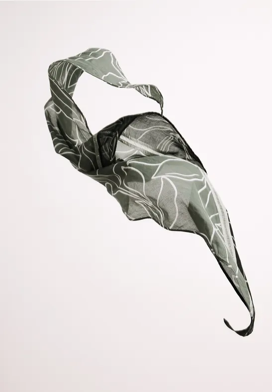 Lekka zielona tkanina w liściasty wzór unosząca się w powietrzu na jasnym tle