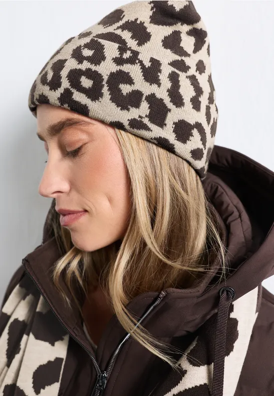 Frau im Profil trägt beige-braune Leopardenmuster-Mütze und passende Jacke