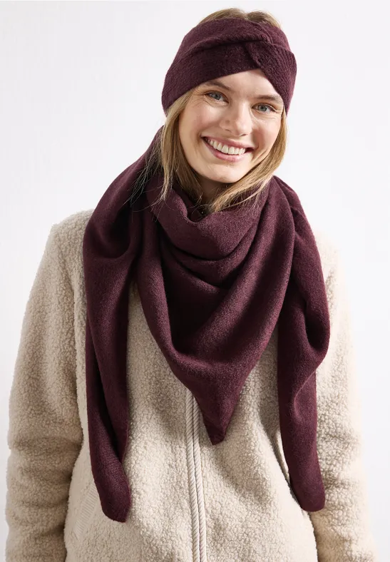 Femme souriante en veste teddy beige, bandeau et châle triangle violets, sur fond blanc.