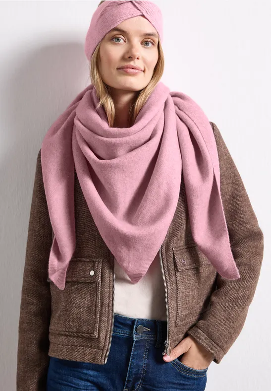 Vrouw met roze sjaal en bijpassende tulband, bruine jas en wit overhemd.