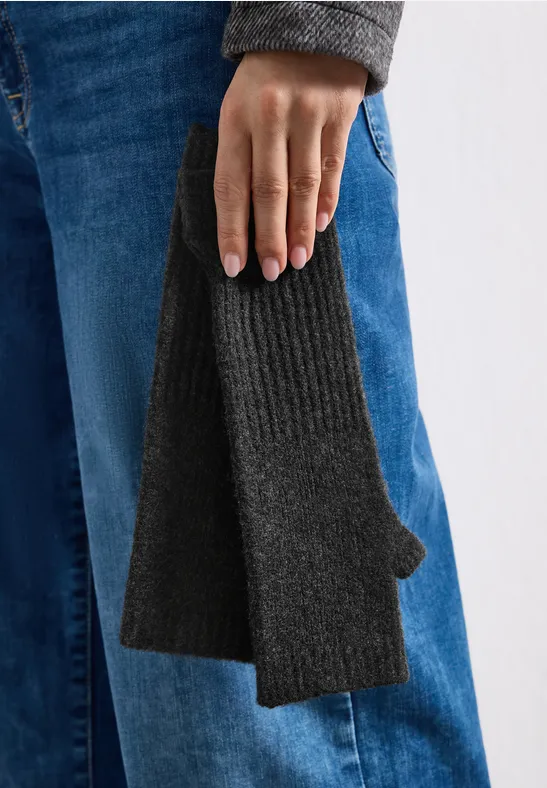 Nahaufnahme einer Hand in Jeans, die einen dunkelgrauen Strick-Handschuh mit Daumenloch hält.