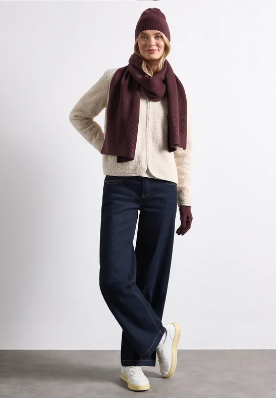 Jeune femme en tenue hivernale : bonnet, écharpe, veste, jeans et baskets