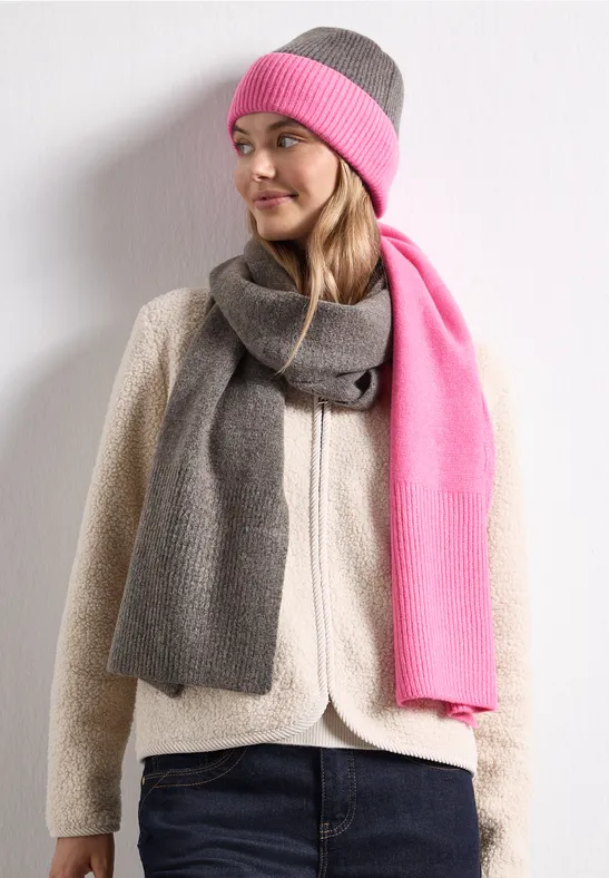 Frau mit grauer und pinker Wintermütze, passendem Schal und Fleecejacke schaut seitlich.