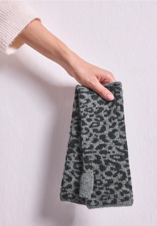 Eine Hand hält ein graues, flauschiges Stirnband mit Leopardenmuster.