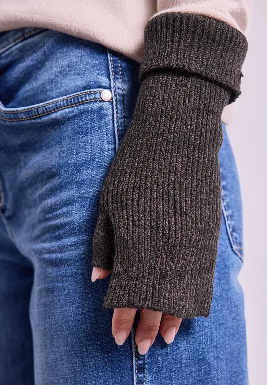 Gestrickter, dunkelgrauer Fingerhandschuh aus Wolle an einer Hand über blauer Jeans.