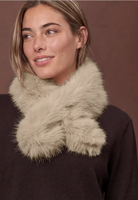 Eine Frau mit leicht lächelndem Blick trägt einen flauschig-beigen Schal um den Hals.