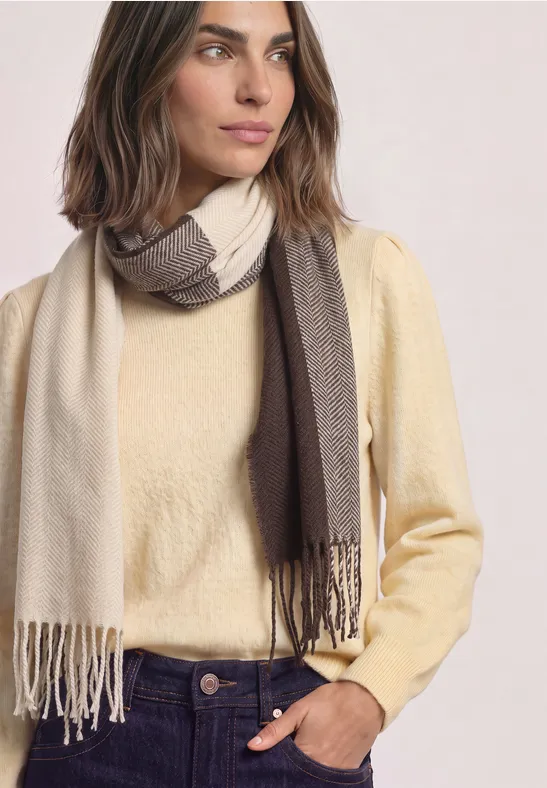 Person mit cremegelbem Pullover und zweifarbigem Schal
