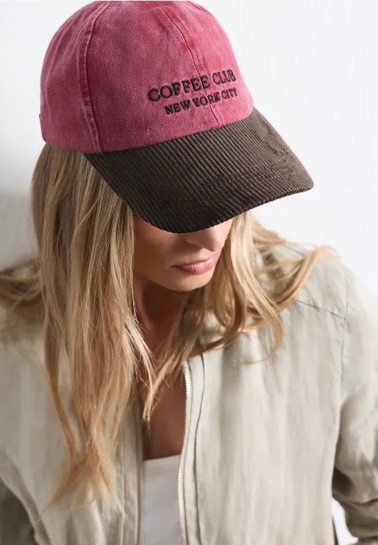 Frau mit blonden Haaren trägt zweifarbige Baseballcap mit Aufschrift "COFFEE CLUB"