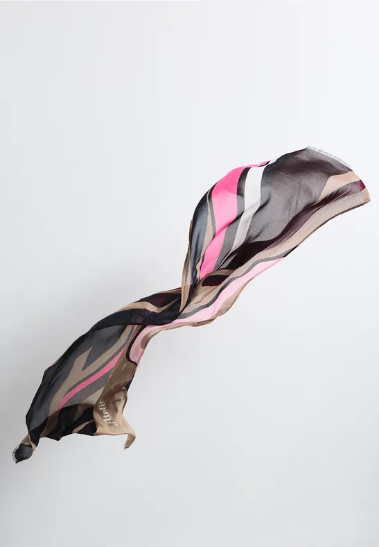 Ein schwebendes, gemustertes Seidentuch in Schwarz, Pink und Grau vor weißem Hintergrund.