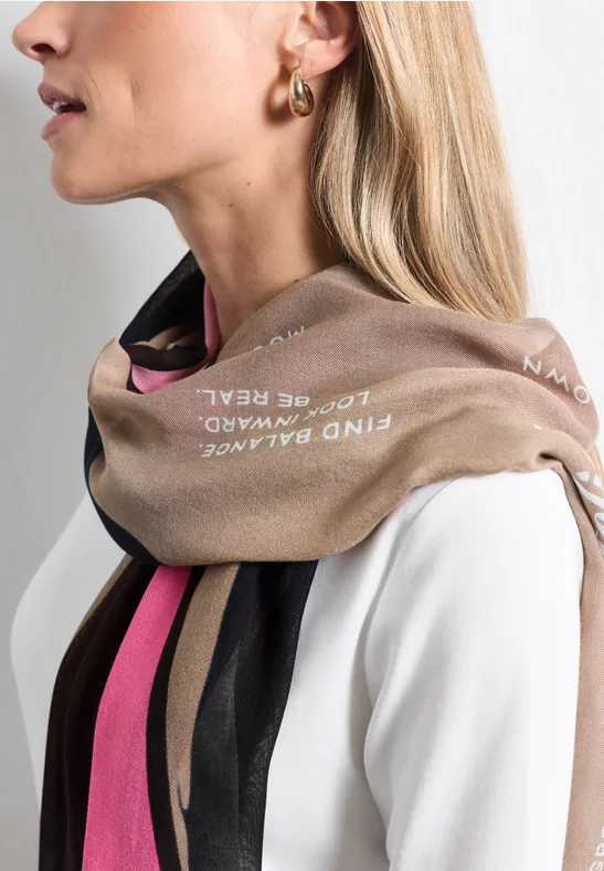 Frau im Profil mit weißem Oberteil, Schal in Beige, Schwarz und Pink sowie goldener Creole.