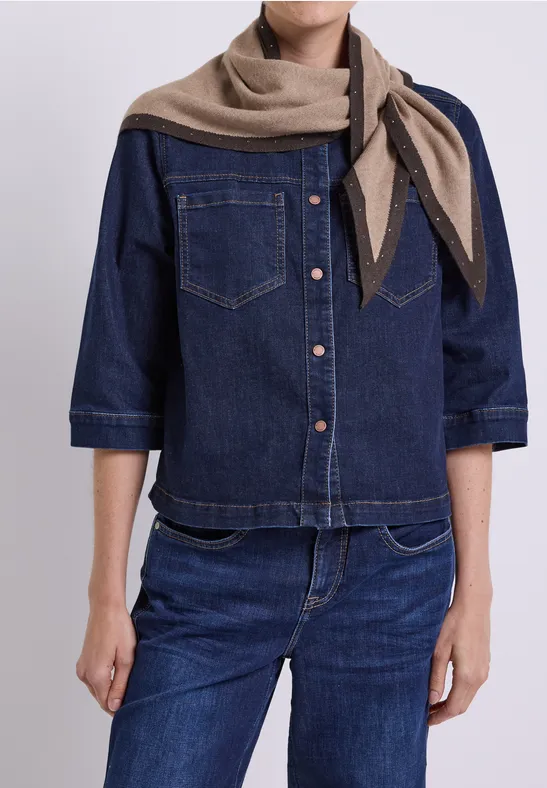 Personne portant une chemise en jean bleue, un jean et une écharpe beige.