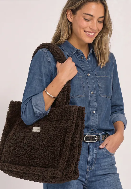 Frau in Jeans-Outfit mit großem flauschigem braunen Schulterbeutel