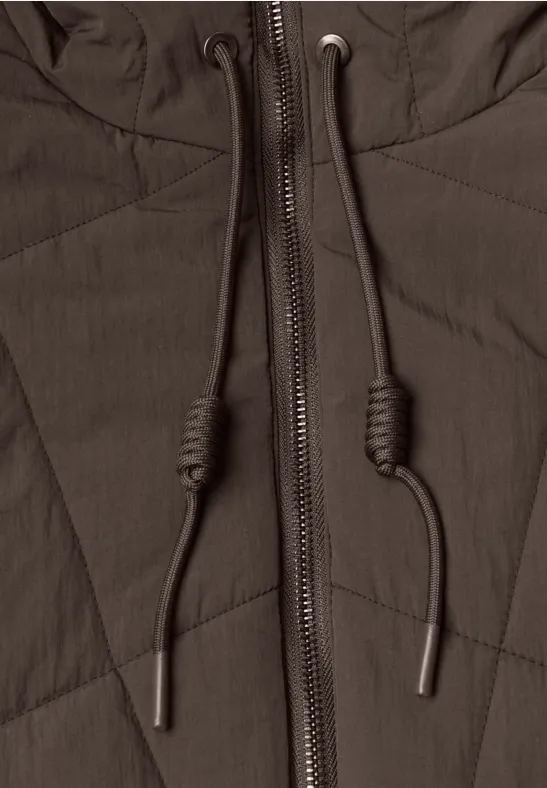 Nahaufnahme einer dunkelbraunen Steppjacke mit Reißverschluss und Kapuzenbändern.