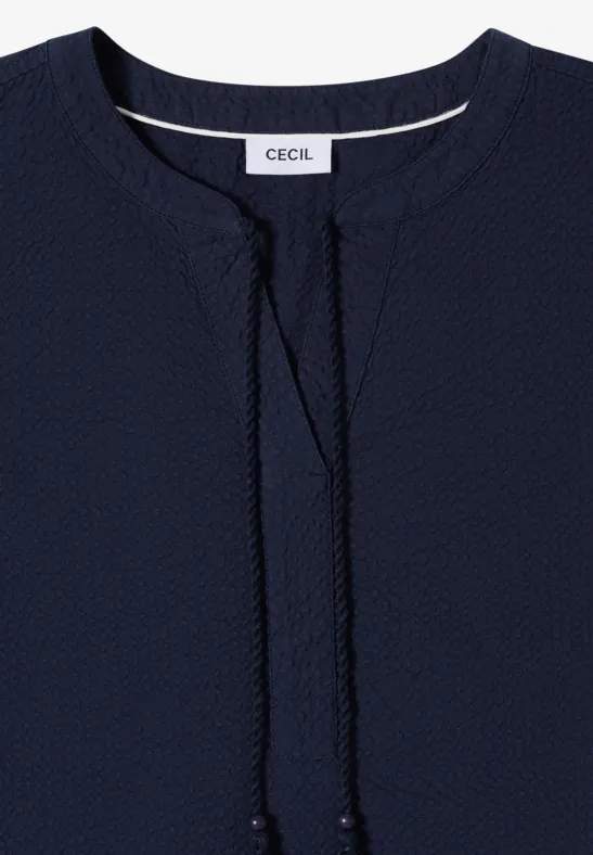 Dunkelblaues Damenoberteil mit rundem Ausschnitt, V-förmigem Schlitz mit Kordeln und Label „CECIL“.