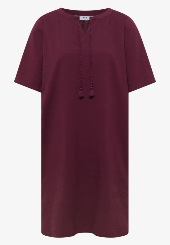 Bordeauxrotes, gerade geschnittenes Tunikakleid mit kurzem Arm und Quastenbändern am V-Ausschnitt.