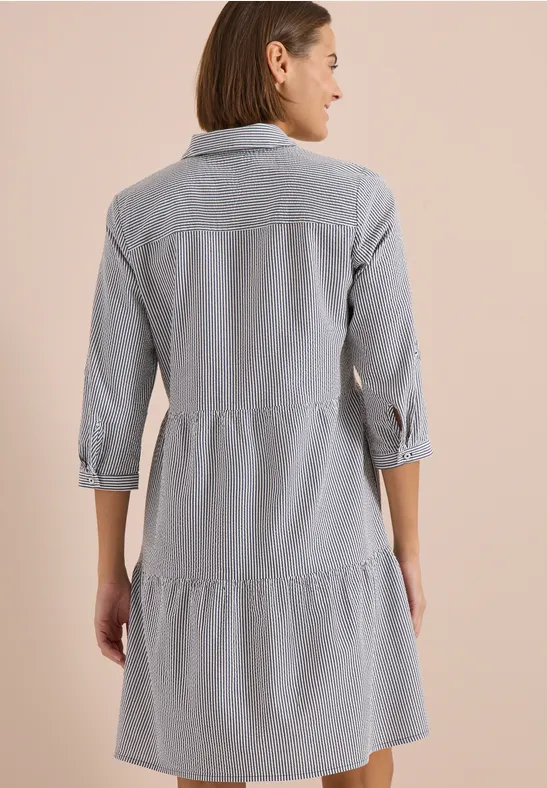 Rückansicht einer Frau in locker sitzendem, gestreiftem Kleid mit Stufenrock und dreiviertel Ärmeln.