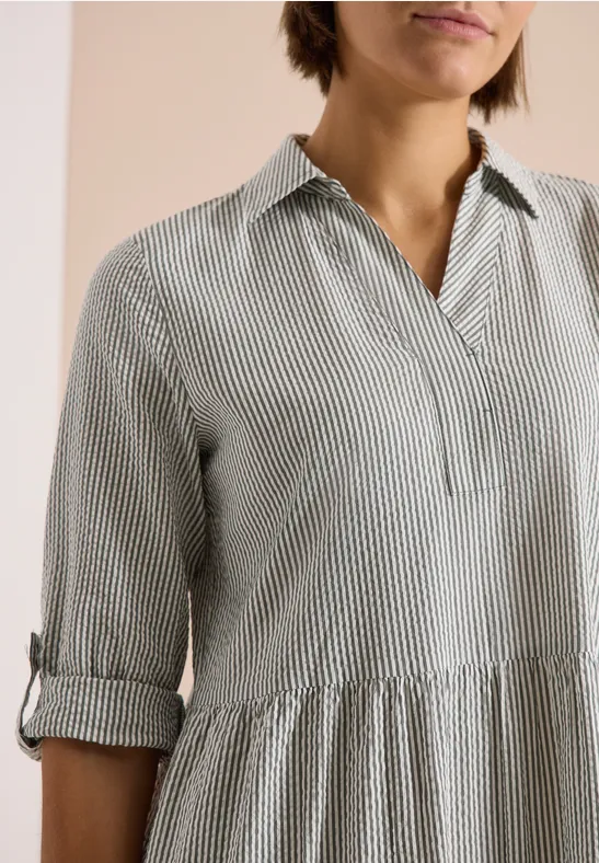 Leichte Bluse mit feinen Grün-Weiß-Streifen, V-Ausschnitt, geraffter Taille und hochgekrempelten Ärmeln.