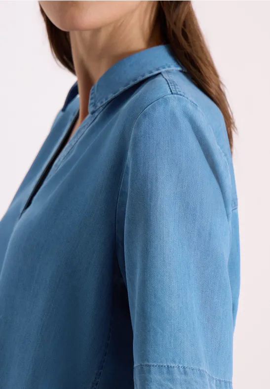 Vue latérale d'une personne portant une chemise en jean bleu clair à manches longues.