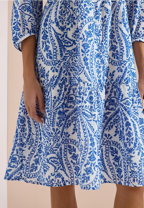 Weißes Sommerkleid mit blauem Paisley- und Blattmuster, leicht fallend.