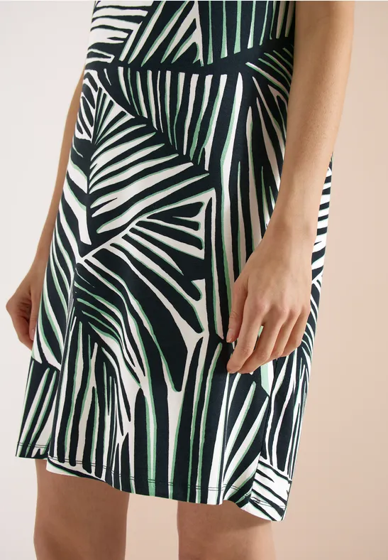 Gros plan sur une robe à motif de feuilles de palmier vertes sur fond blanc.