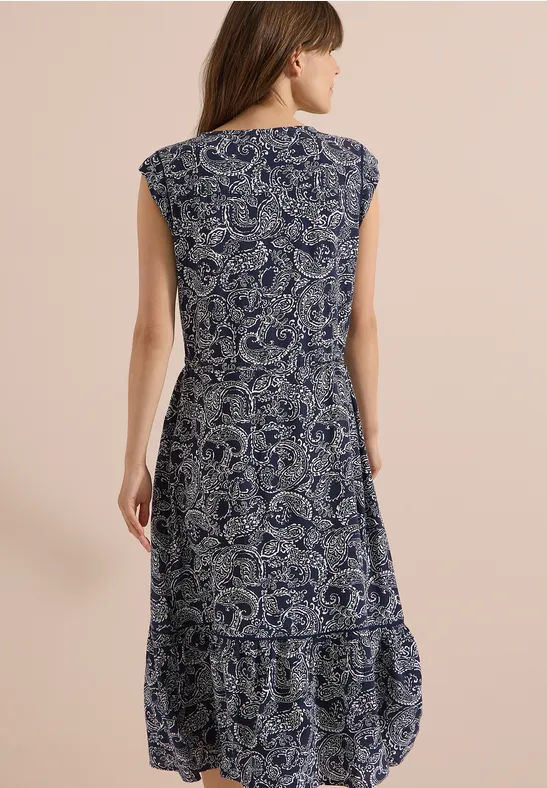 Femme de dos portant une robe sans manches mi-longue bleu marine à motif cachemire blanc.