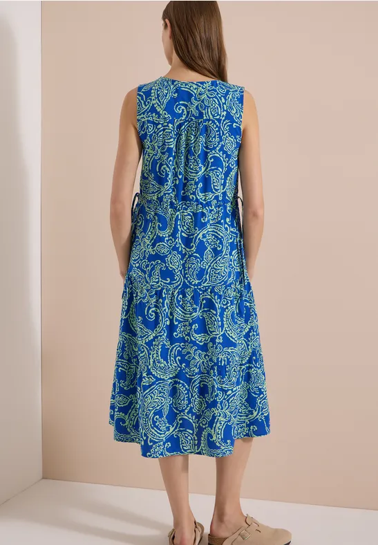 Femme de dos portant une robe sans manches bleu-vert à motifs paisley.