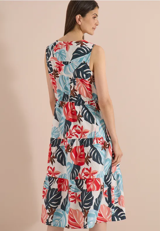 Frau von hinten in ärmellosem, gestuftem Sommerkleid mit buntem Blumenmuster.