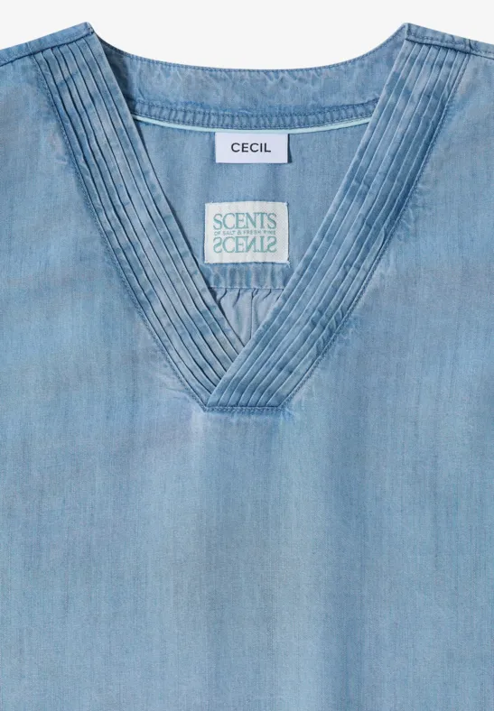 Haut en jean bleu clair à encolure en V et finitions surpiquées au col.