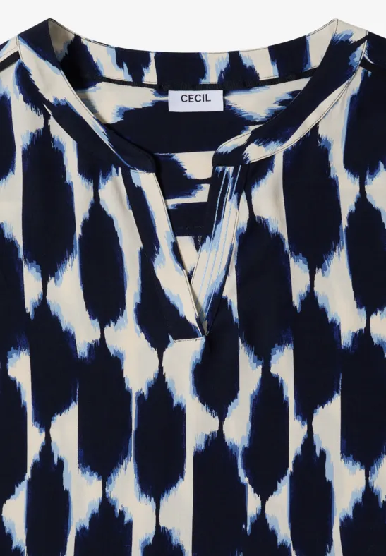 Chemisier blanc à motif tacheté abstrait bleu marine, encolure ronde fendue et coupe décontractée.