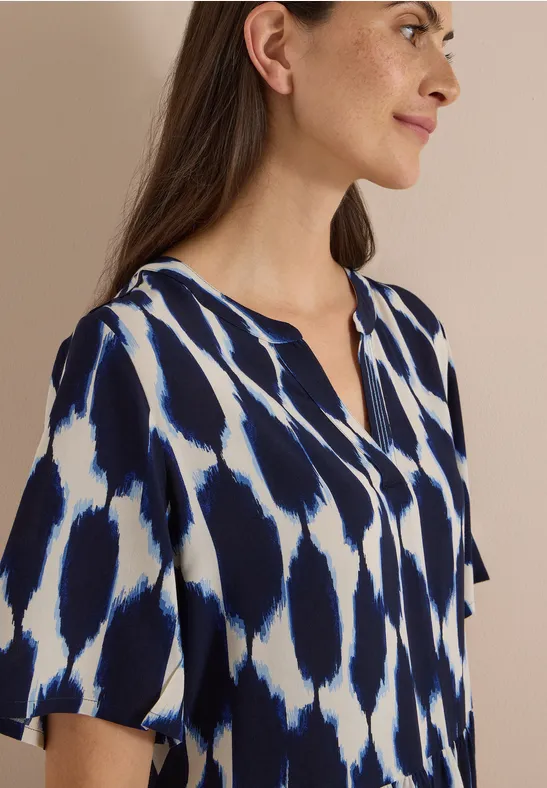 Femme en chemisier bleu marine et blanc à manches courtes et encolure V.