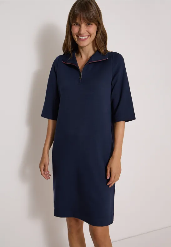 Femme portant une robe bleue marine mi-longue à manches mi-longues et col zippé