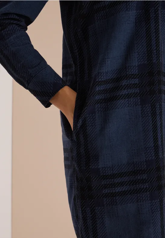 Robe à manches longues bleu foncé à carreaux, poche latérale avec main à l’intérieur.