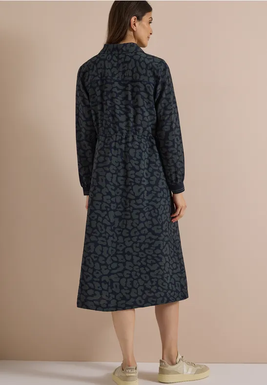 Femme de dos portant une robe midi bleu foncé imprimée à manches longues et col.
