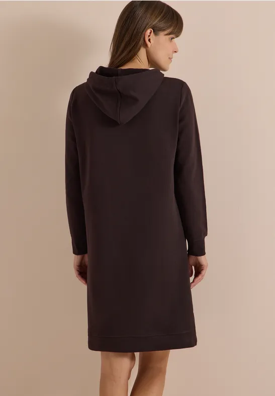 Femme de dos portant une robe à capuche brun foncé arrivant aux genoux, manches longues.
