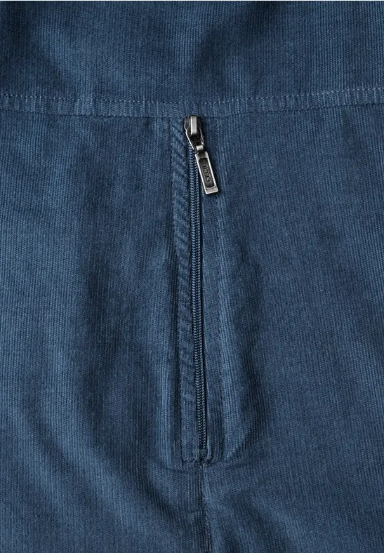 Gros plan d'une veste en tissu côtelé bleu avec poche zippée verticale
