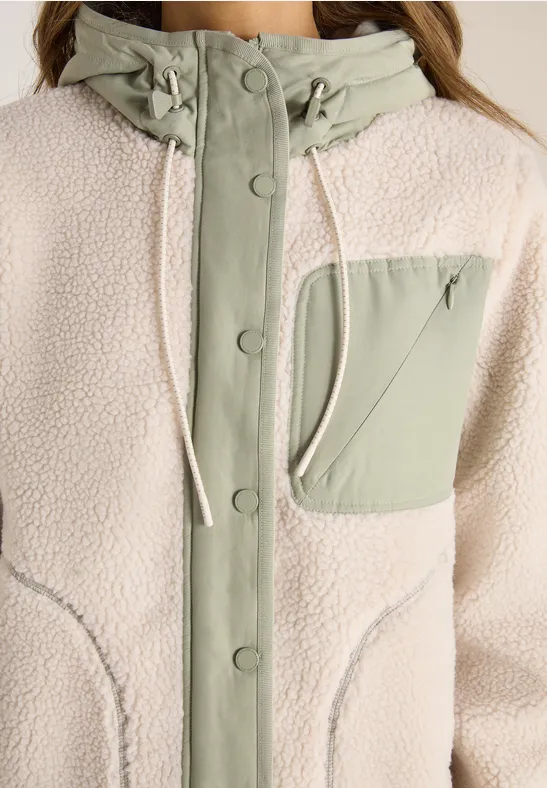 Damen-Fleecejacke in Creme mit hellgrünen Akzenten, Stehkragen mit Kapuze und Druckknopfleiste.