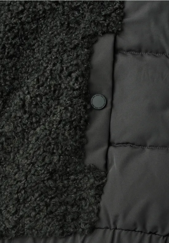 Nahaufnahme einer schwarzen Jacke mit Fleece- und Steppstoff-Einsätzen und einem Druckknopf.