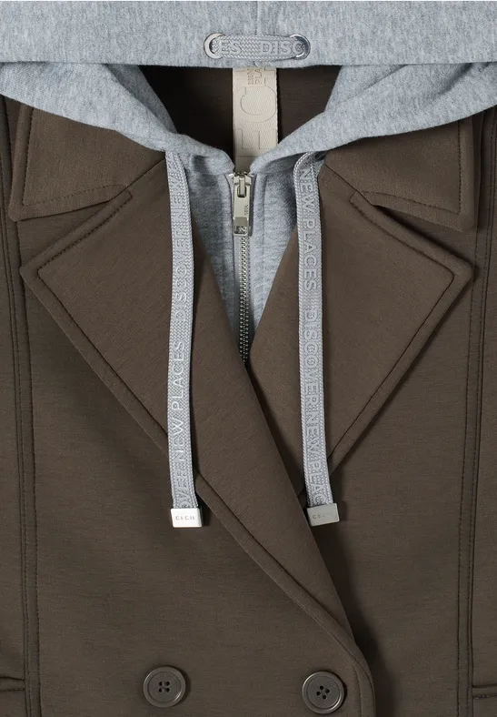 Nahaufnahme eines braunen Blazers mit grauer Kapuze und Kordeln, Doppelreiher mit zwei Knöpfen.